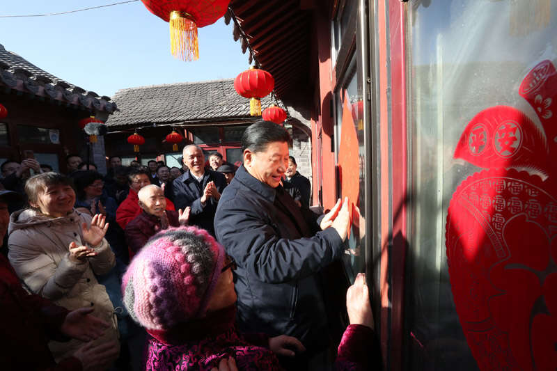 2019年2月1日上午，習近平在北京前門東區(qū)草廠四條胡同32號院，高興地拿起一幅“?！弊?，親自貼到門上，給這里的老街坊們拜年。新華社記者 鞠鵬 攝